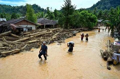 Warga berjalan di tengah banjir bandang di Desa Tukka, Tapanuli Tengah, Provinsi Sumatera Utara, Selasa (02/12/2025).