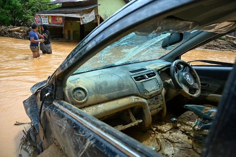 Warga berjalan di tengah banjir bandang di Desa Tukka, Tapanuli Tengah, Provinsi Sumatera Utara, Selasa (02/12/2025).