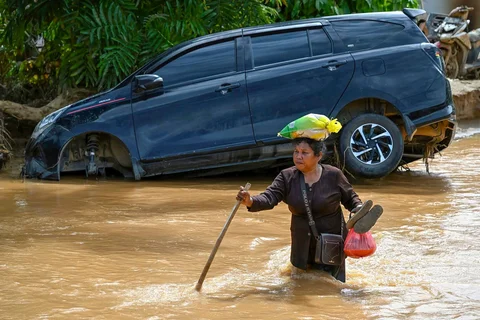 Warga berjalan di tengah banjir bandang di Desa Tukka, Tapanuli Tengah, Provinsi Sumatera Utara, Selasa (02/12/2025).