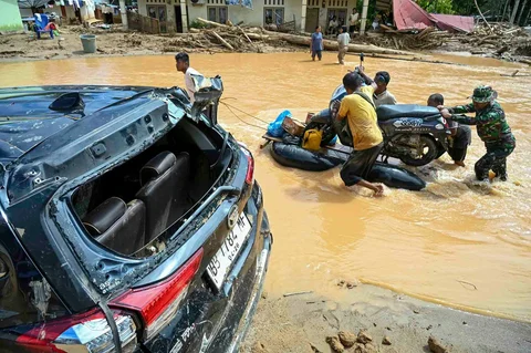Warga berjalan di tengah banjir bandang di Desa Tukka, Tapanuli Tengah, Provinsi Sumatera Utara, Selasa (02/12/2025).