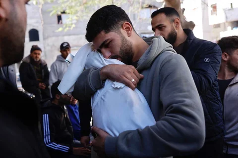Seorang pria Palestina menggendong jenazah adiknya yang berusia 5 bulan, Ahmed Al-Nader, yang dilaporkan tewas sehari sebelumnya bersama anggota keluarga lainnya dalam serangan artileri Israel terhadap sebuah sekolah yang dijadikan tempat perlindungan di lingkungan Tuffah, Kota Gaza, Sabtu (20/12/2025).