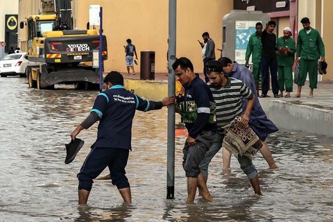 Orang-orang menerobos genangan air banjir setelah hujan lebat di Dubai, Uni Emirat Arab (UEA) pada Jumat 19 Desember 2025. Hujan lebat yang terjadi pada Jumat 19 Desember 2025 berimbas pada g