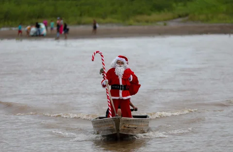 Relawan Jorge Alberto Barrozo, yang mengenakan kostum Sinterklas, berlayar dengan kano mengantarkan hadiah kepada anak-anak di komunitas tepi sungai di daerah pedesaan Careiro da Varzea, negara bagian Amazonas, Brasil, Sabtu (20/12/2025) waktu setempat.