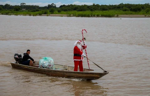 Relawan Jorge Alberto Barrozo, yang mengenakan kostum Sinterklas, berlayar dengan kano mengantarkan hadiah kepada anak-anak di komunitas tepi sungai di daerah pedesaan Careiro da Varzea, negara bagian Amazonas, Brasil, Sabtu (20/12/2025) waktu setempat.