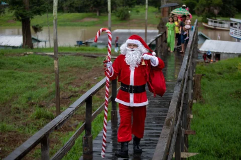 Relawan Jorge Alberto Barrozo, yang mengenakan kostum Sinterklas, mengantarkan hadiah kepada anak-anak di komunitas tepi sungai di daerah pedesaan Careiro da Varzea, negara bagian Amazonas, Brasil, Sabtu (20/12/2025) waktu setempat.