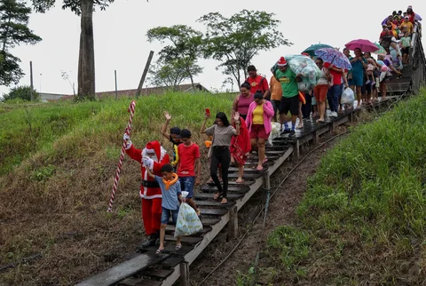 Relawan Jorge Alberto Barrozo, yang mengenakan kostum Sinterklas, mengantarkan hadiah kepada anak-anak di komunitas tepi sungai di daerah pedesaan Careiro da Varzea, negara bagian Amazonas, Brasil, Sabtu (20/12/2025) waktu setempat.