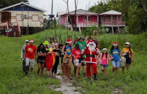 Relawan Jorge Alberto Barrozo, yang mengenakan kostum Sinterklas, mengantarkan hadiah kepada anak-anak di komunitas tepi sungai di daerah pedesaan Careiro da Varzea, negara bagian Amazonas, Brasil, Sabtu (20/12/2025) waktu setempat.