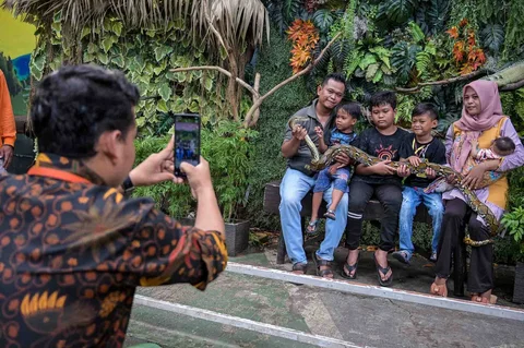 Pengunjung berfoto dengan ular sanca di Kebun Binatang Surabaya selama liburan Natal dan Tahun Baru di Surabaya Minggu (21/12/2025).