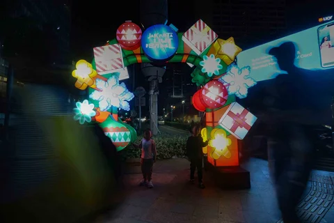 Warga menikmati suasana Jakarta Light Festival 2025 di sekitar Bundaran Hotel Indonesia, Jakarta, Selasa (23/12/2025).