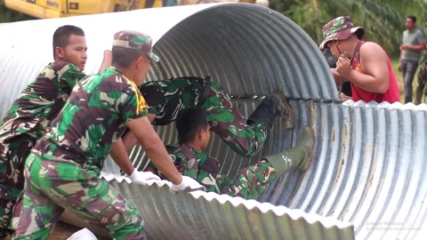 Personel Kodim 0104/Aceh Timur bersama Yonif TP 853/Bawar Reje Bur saat menyelesaikan pembangunan jembatan Armco di Dusun Leupon, Gampong Bukit Kuta, Aceh Timur, Selasa (23/12/2025).
