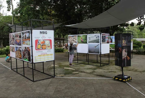 Pengunjung menyaksikan beragam karya jurnalistik dalam pameran Haluan Merah Putih Roadshow yang digelar di Selasar Kantin Taman Margasatwa Ragunan, Jakarta Selatan, Selasa (24/12/2025).