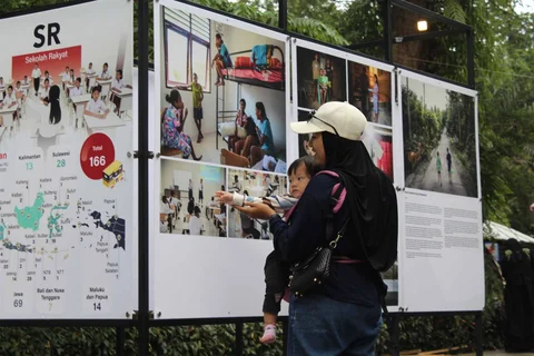 Pengunjung menyaksikan beragam karya jurnalistik dalam pameran Haluan Merah Putih Roadshow yang digelar di Selasar Kantin Taman Margasatwa Ragunan, Jakarta Selatan, Selasa (24/12/2025).