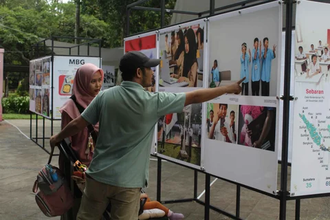 Pengunjung menyaksikan beragam karya jurnalistik dalam pameran Haluan Merah Putih Roadshow yang digelar di Selasar Kantin Taman Margasatwa Ragunan, Jakarta Selatan, Selasa (24/12/2025).
