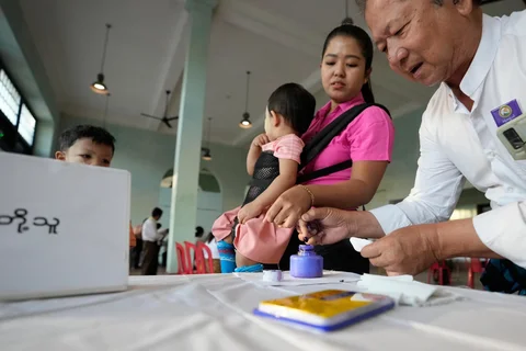 Seorang pemilih mencelupkan jarinya ke dalam botol tinta setelah memberikan suara di tempat pemungutan suara pada hari Minggu (28/12/2025) di Yangon, Myanmar.