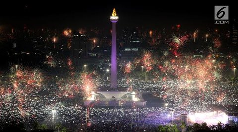Pengunjung menyaksikan pesta kembang api saat malam Tahun Baru 2019 di Pantai Lagoon, Ancol, Jakarta, Selasa (1/1). Ancol menyajikan pesta kembang api musikal sepanjang 600 meter di bibir pan