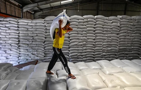 Pekerja membawa karung-karung beras di gudang Badan Logistik Indonesia (Bulog) di Lambaro, Provinsi Aceh, Senin (29/12/2025).
