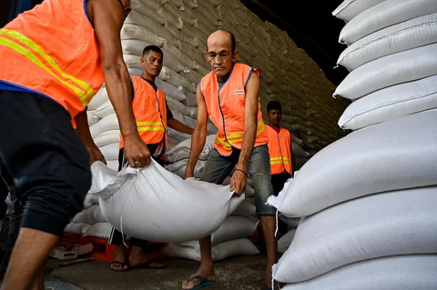 Pekerja membawa karung-karung beras di gudang Badan Logistik Indonesia (Bulog) di Lambaro, Provinsi Aceh, Senin (29/12/2025).