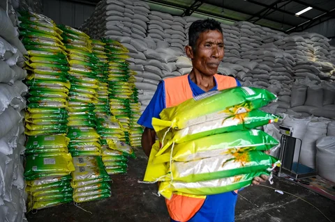 Pekerja membawa karung-karung beras di gudang Badan Logistik Indonesia (Bulog) di Lambaro, Provinsi Aceh, Senin (29/12/2025).