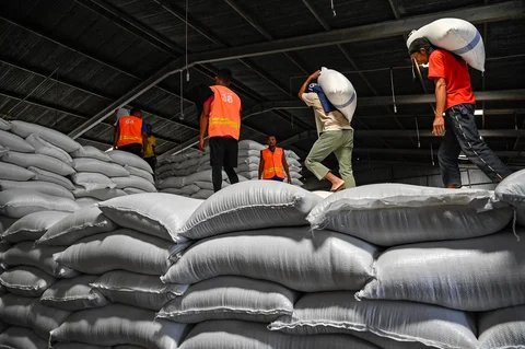 Pekerja membawa karung-karung beras di gudang Badan Logistik Indonesia (Bulog) di Lambaro, Provinsi Aceh, Senin (29/12/2025).
