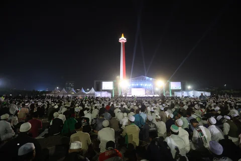 Warga membacakan sholawat nabi saat mengikuti Reuni 212 di Monas, Jakarta, Selasa (2/12/2025) malam.