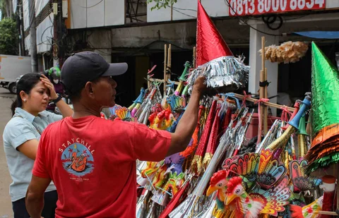 Pedagang melayani pembeli terompet dagangannya di kawasan Glodok, Jakarta, Selasa (30/12/2025