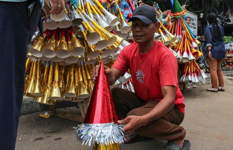 Pedagang melayani pembeli terompet dagangannya di kawasan Glodok, Jakarta, Selasa (30/12/2025