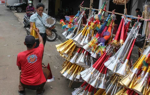 Pedagang melayani pembeli terompet dagangannya di kawasan Glodok, Jakarta, Selasa (30/12/2025