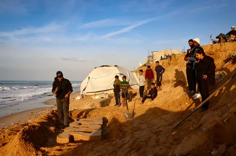 Seniman Yazed Abo Jarad (kiri) membuat patung pasir untuk tahun 2026  saat pengungsi Palestina bersiap menyambut Tahun Baru di Deir El-Balah di Jalur Gaza tengah, Selasa (30/12/2025).