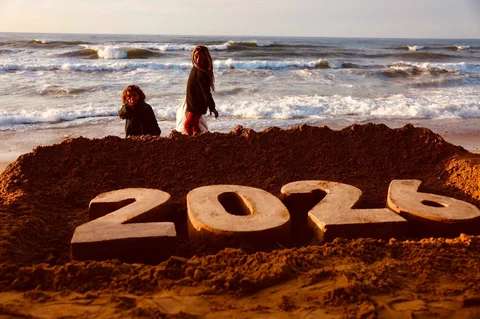 Anak-anak berdiri di samping patung pasir saat pengungsi Palestina bersiap menyambut Tahun Baru di Deir El-Balah di Jalur Gaza tengah, Selasa (30/12/2025).
