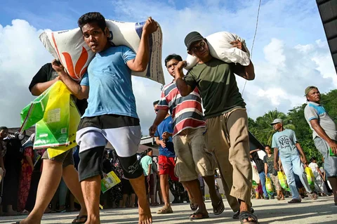 Warga desa menerima karung beras gratis yang didistribusikan dari gudang beras Bulog di Sarudik, Tapanuli Tengah, Provinsi Sumatera Utara, Rabu (03/12/2025).
