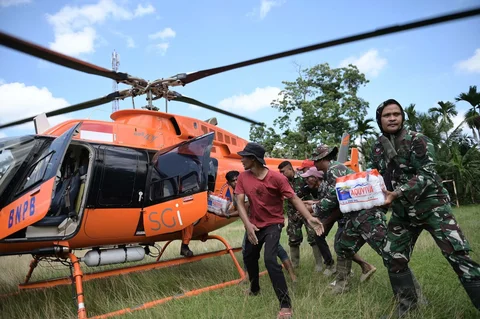 Prajurit TNI AD dan warga menurunkan barang bantuan dari helikopter Badan Nasional Penanggulangan Bencana (BNPB) saat distribusi bantuan udara di wilayah terdampak banjir di Aceh Utara, Indonesia, Kamis (04/12/2025).