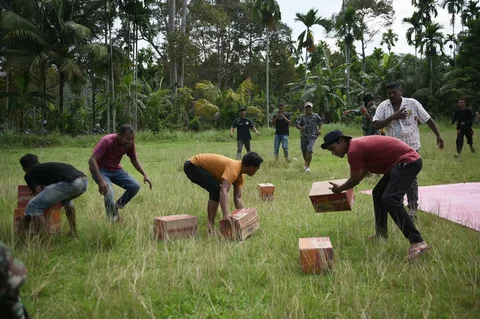 Tentara dan warga menurunkan barang bantuan dari helikopter Badan Nasional Penanggulangan Bencana (BNPB) saat distribusi bantuan udara di wilayah terdampak banjir di Aceh Utara, Indonesia, Kamis (04/12/2025).