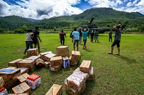 Warga membawa bantuan yang didistribusikan helikopter  TNI AU di wilayah terdampak banjir di Kabupaten Bener Meriah, Provinsi Aceh,Kamis (04/12/2025).