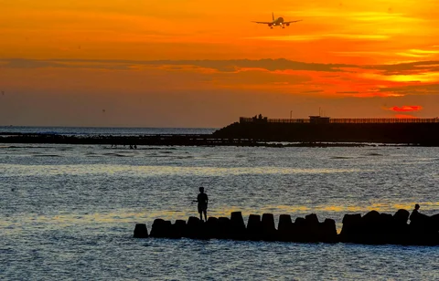 Wisatawan  duduk pada beton abrasi pantai menyaksikan suasana senja  di Pantai Kelan, Badung, Bali.