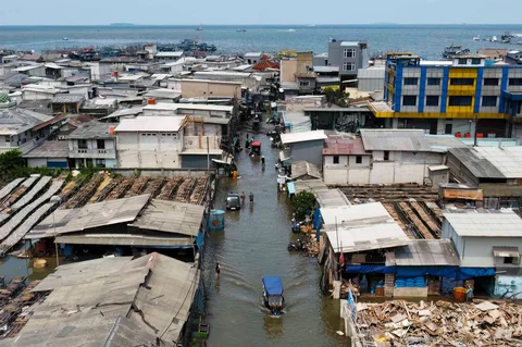 Warga melintasi genangan saat banjir rob di Muara Baru, Jakarta, Sabtu (06/12/2025).