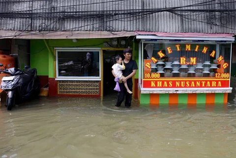Warga melintasi genangan saat banjir rob di Muara Baru, Jakarta, Sabtu (06/12/2025).