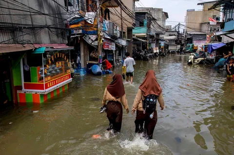 Warga melintasi genangan saat banjir rob di Muara Baru, Jakarta, Sabtu (06/12/2025).