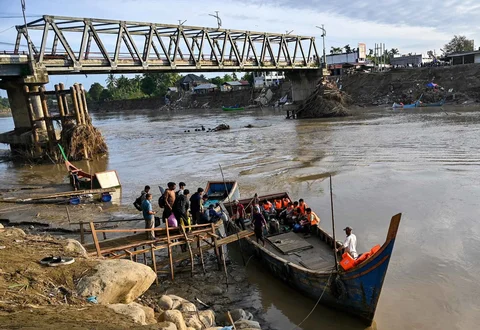 Warga menyeberangi Sungai Peusangan dengan perahu nelayan di Kuta Blang, Kabupaten Bireuen, Provinsi Aceh, Selasa (09/12/2025).