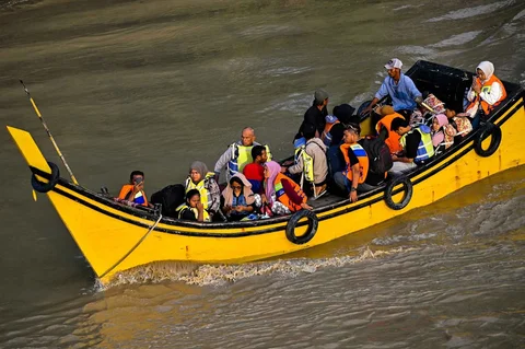 Warga menyeberangi Sungai Peusangan dengan perahu nelayan di Kuta Blang, Kabupaten Bireuen, Provinsi Aceh, Selasa (09/12/2025).