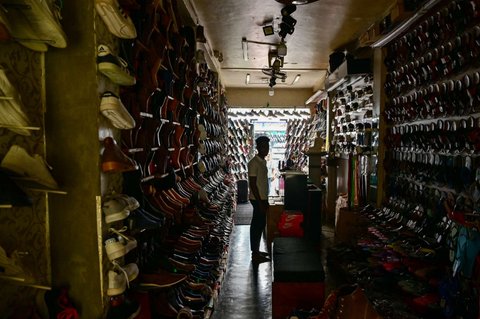 Seorang pria menunggu pelanggan di toko alas kaki yang redup selama pemadaman listrik nasional gara-gara seekor monyet di Galle, Sri Lanka, pada 9 Februari 2025.