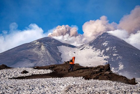 Seorang pria berjalan di depan Gunung Etna yang erupsi di Sisilia, italia, 1(12/02/2025).