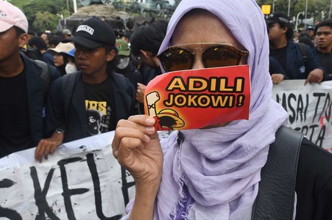Seorang mahasiswa menunjukkan stiker bertuliskan 