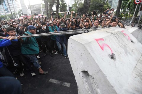 Mahasiswa bersama-sama merobohkan barikade beton selama aksi demo 'Indonesia Gelap' di kawasan Patung Kuda, Jakarta, Kamis (20/2/2025).