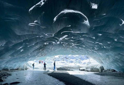 Pendaki berjalan dalam gua es yang terbentuk oleh air saat musim panas pada gletser Morteratsch yang  mencair akibat perubahan iklim di Pegunungan Alpen, Swiss, Sabtu (21/02/ 2025) waktu setempat.