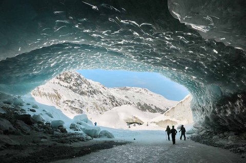 Pendaki berjalan dalam gua es yang terbentuk oleh air saat musim panas pada gletser Morteratsch yang  mencair akibat perubahan iklim di Pegunungan Alpen, Swiss, Sabtu (21/02/ 2025) waktu setempat