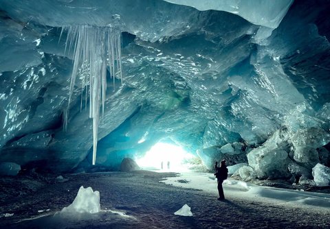 Pendaki berjalan dalam gua es yang terbentuk oleh air saat musim panas pada gletser Morteratsch yang  mencair akibat perubahan iklim di Pegunungan Alpen, Swiss, Sabtu (21/02/ 2025) waktu setempat