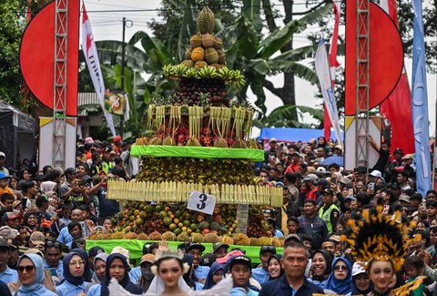 Warga mengarak durian dan buah-buahan lainnya saat festival durian "Kenduren Wonosalam" di desa Wonosalam, Jombang,  Jawa Timur, (23/ 02/ 2025).