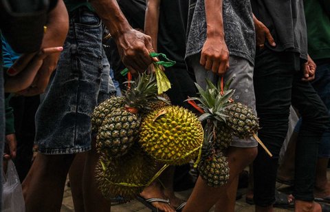 Warga membawa durian dan buah-buahan lainnya usai dibagikan gratis saat festival durian "Kenduren Wonosalam" di desa Wonosalam, Jombang,  Jawa Timur, (23/ 02/ 2025).