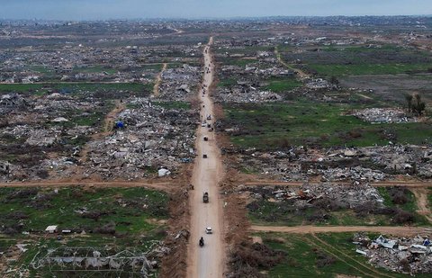 Pemandangan dari drone warga Palestina berjalan melewati reruntuhan setelah pasukan Israel mundur dari Koridor Netzarim, dekat Kota Gaza, Minggu (09/02/2025).