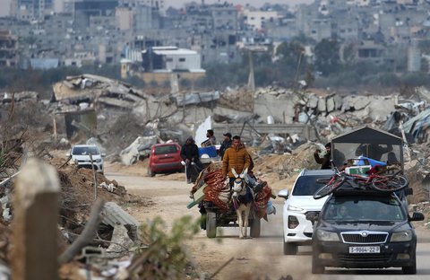 Warga Palestina dengan gerobak berjalan melewati Koridor Netzarim, dekat Kota Gaza, Minggu (09/02/2025).